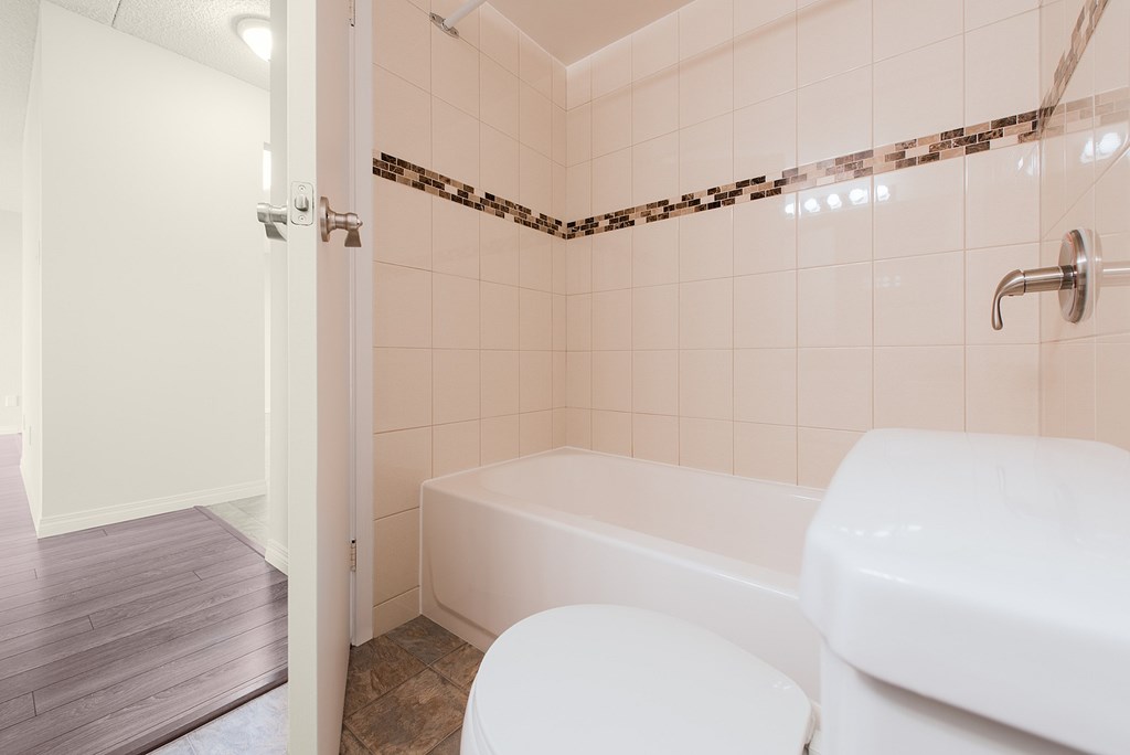 A white toilet sits next to a white bathtub in a bathroom.