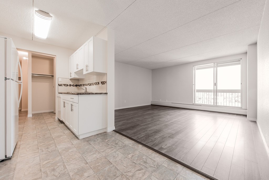 A spacious kitchen with white cabinets and a refrigerator.