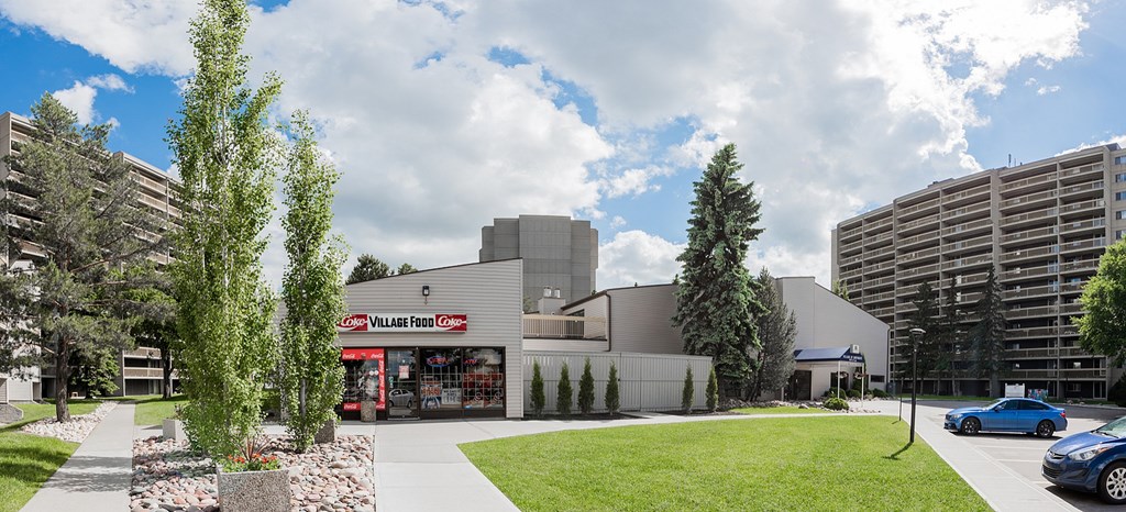 A modern building with a red sign that says "Val Fior" is surrounded by trees and a grassy area.