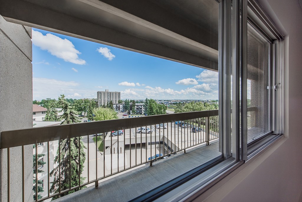 A balcony with a view of a parking lot and buildings.