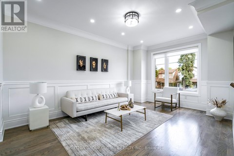 A well-lit, spacious living room with a white sofa and a large window.