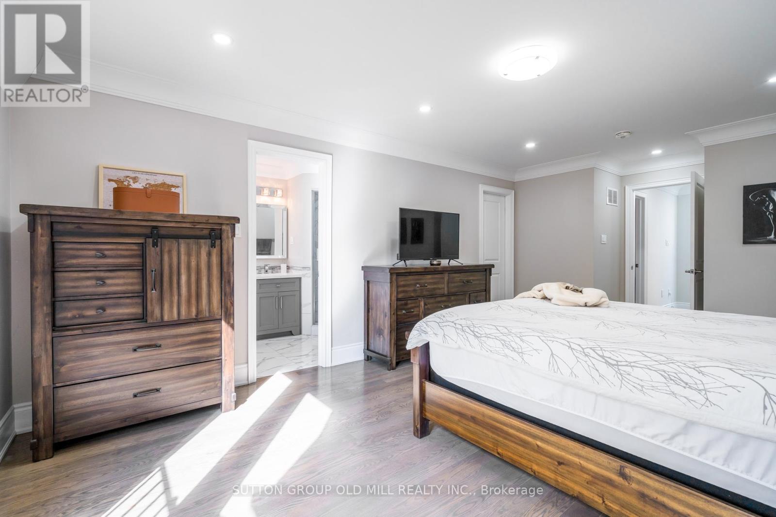 A bedroom with a large bed and a wooden dresser.