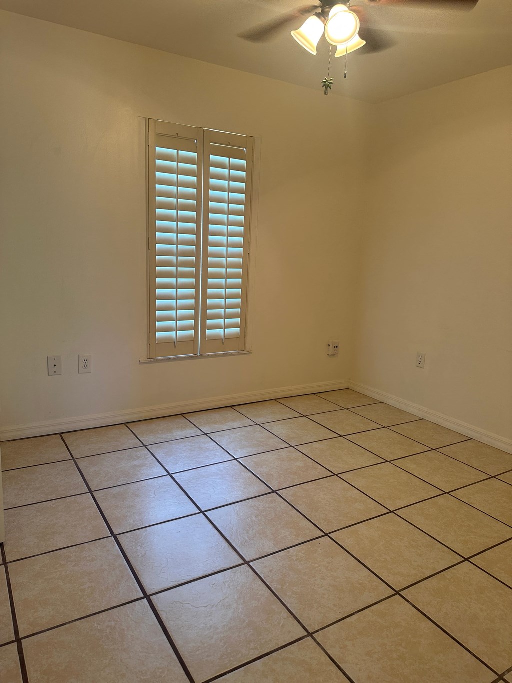 A room with a window and a ceiling fan.