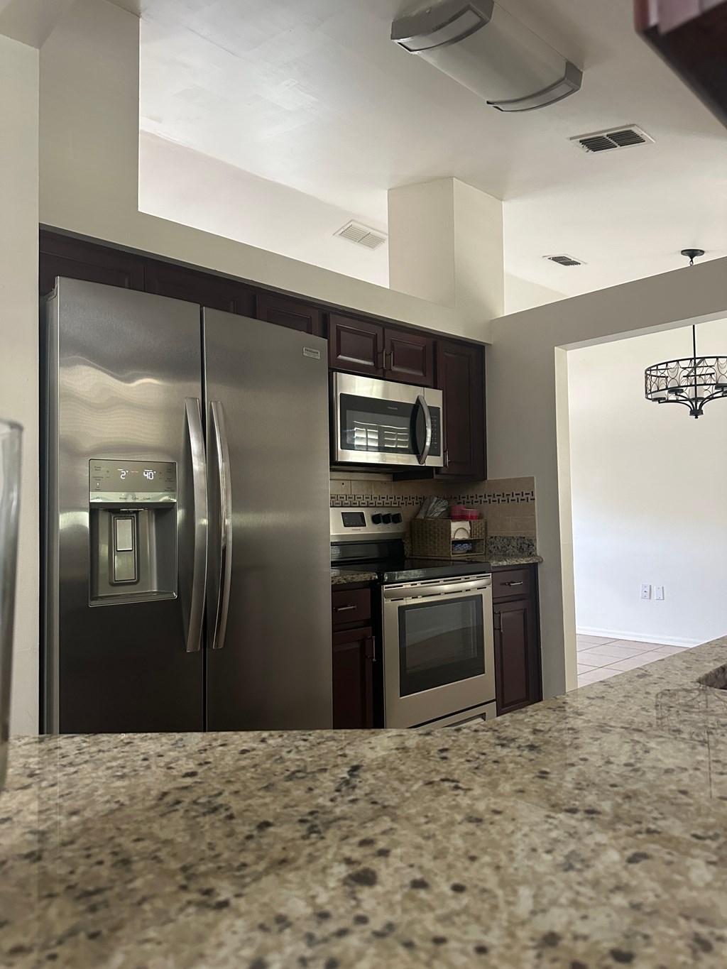 A kitchen with a granite counter top and stainless steel appliances.