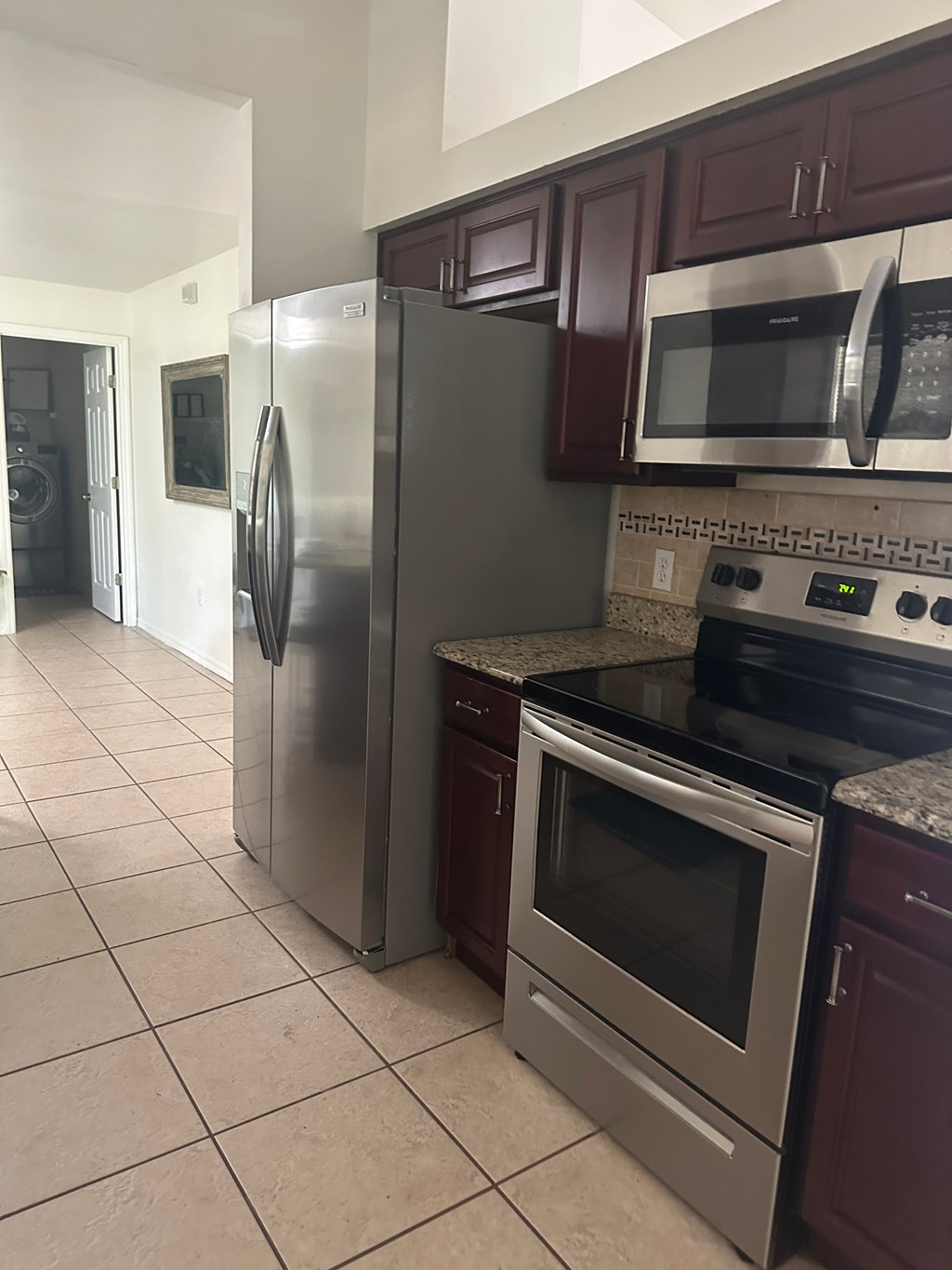 A kitchen with a refrigerator, microwave, oven, and a counter.