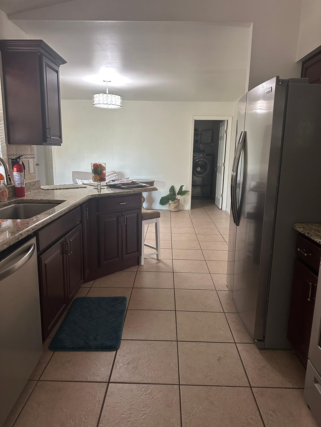 A kitchen with a sink, refrigerator, and a dining table.