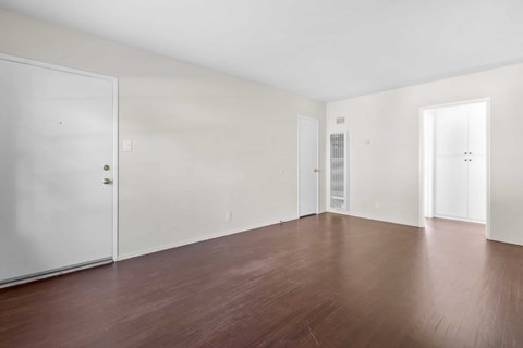 A room with white walls and brown floors.