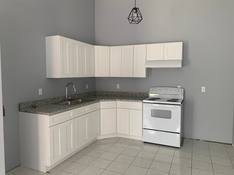 A kitchen with white cabinets and a granite countertop.