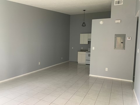 A spacious room with a kitchenette in the background.