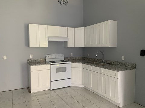 A kitchen with white cabinets and appliances.