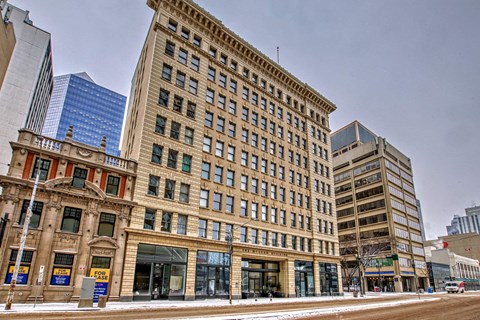 A large, old building with many windows sits in front of a modern skyscraper.