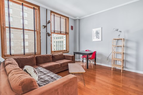 A living room with a brown couch and a table with a red chair.