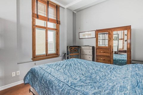 A bedroom with a bed, dresser, and window.