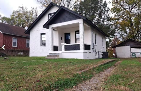 A white house with a black roof and a small porch.