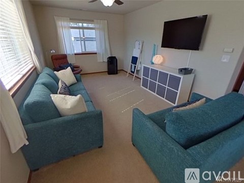 A living room with two blue couches and a flat screen TV mounted on the wall.