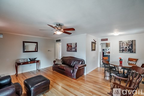A living room with a brown leather couch and a wooden floor.
