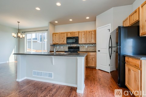 A kitchen with wooden cabinets and a black refrigerator.