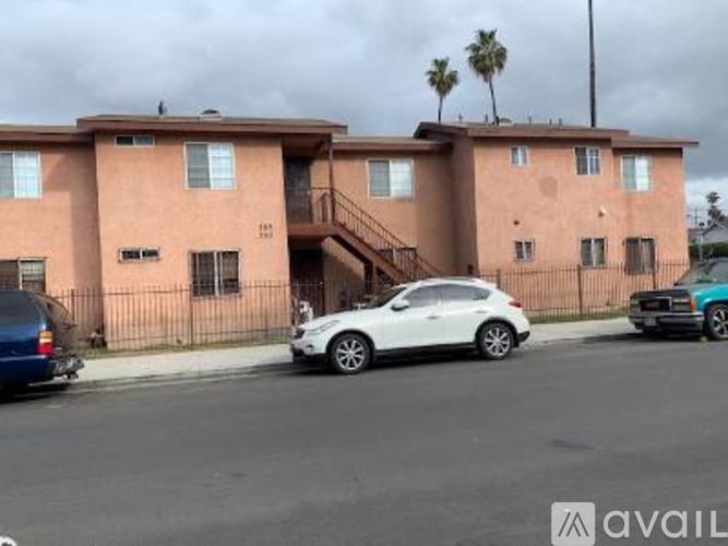 A white car is parked in front of a pink building.