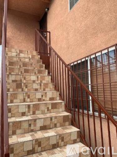 A staircase with a metal railing and steps made of stone or tile.