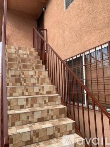 A staircase with a metal railing and steps made of stone or tile.