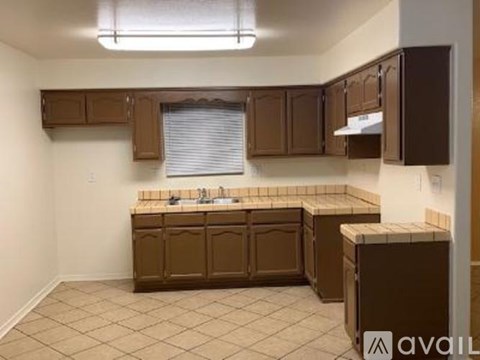 A kitchen with brown cabinets and a tiled floor.