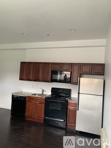 A kitchen with brown cabinets and black appliances.