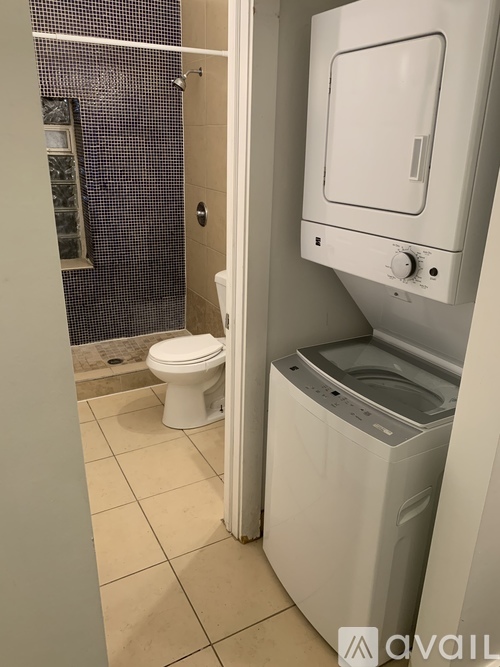 A white toilet and a white washing machine in a small bathroom.
