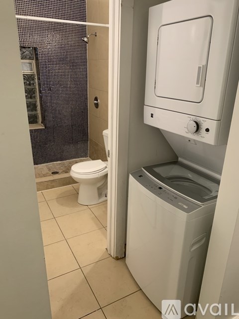 A white toilet and a white washing machine in a small bathroom.