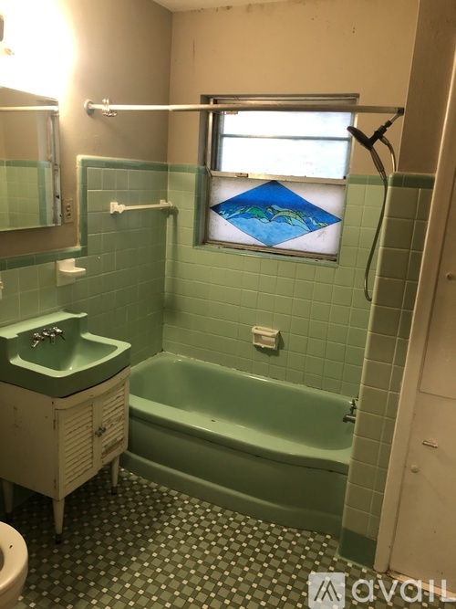 A bathroom with a green tiled shower and a green tub.