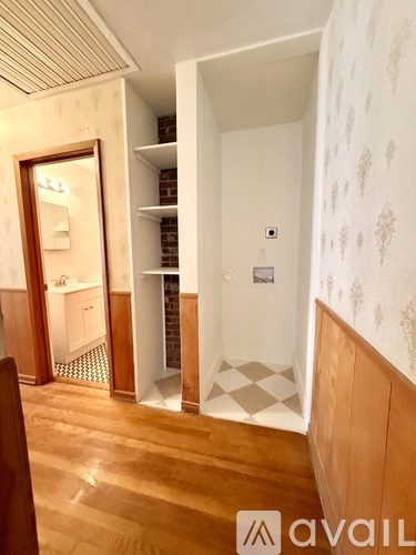 A room with wooden floors and a door leading to another room.
