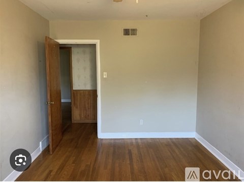 A room with wooden floors and a door leading to another room.