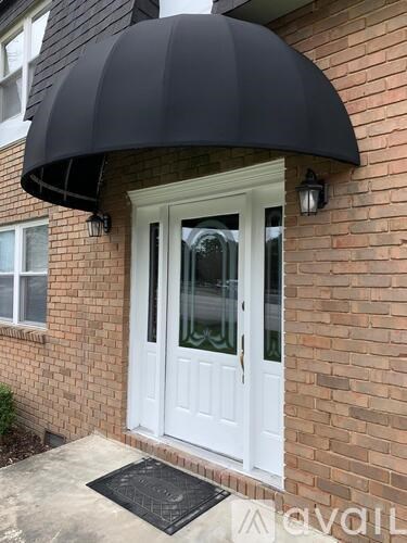 A white door with a black awning is on a brick house.