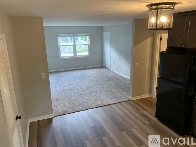 A room with a wooden floor and a black refrigerator.