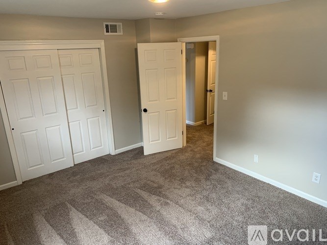 A room with a carpeted floor and two doors.