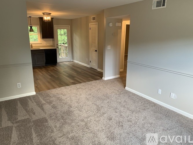 A spacious living room with a kitchen in the background.