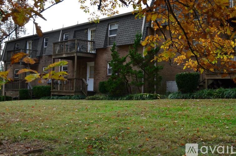 A house with a balcony and a tree with yellow leaves in front.
