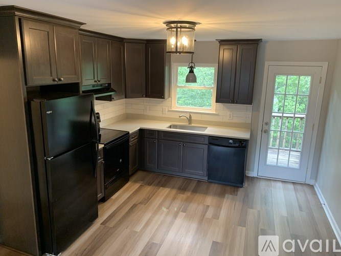 A kitchen with wooden floors and dark brown cabinets.