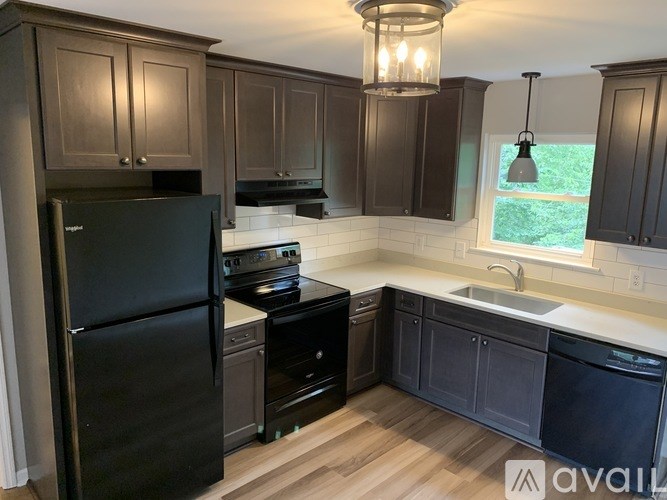 A kitchen with dark brown cabinets and a black refrigerator.