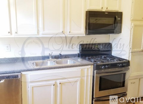 A kitchen with white cabinets and a black microwave above the stove.