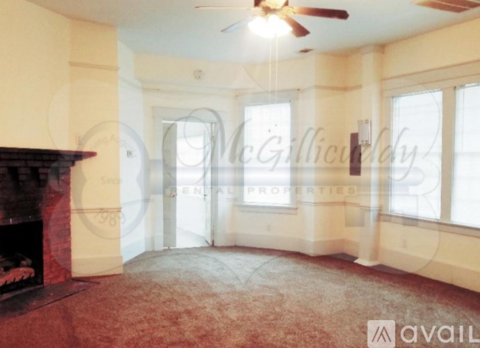 A living room with a fireplace and a ceiling fan.