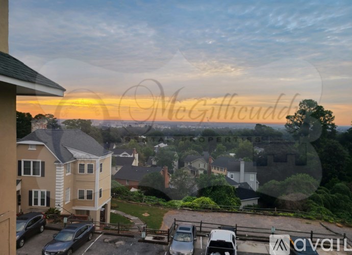 A sunset view from a window overlooking a parking lot and houses.