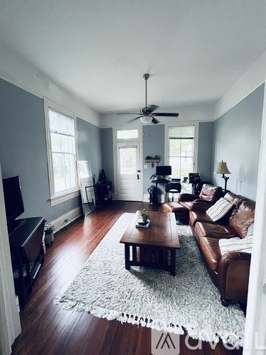 A living room with a brown leather couch and a white rug.