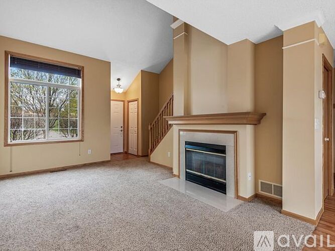 A spacious living room with a fireplace and a staircase.