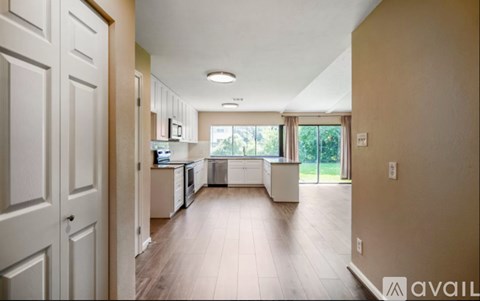 A spacious kitchen with white cabinets and a large window.