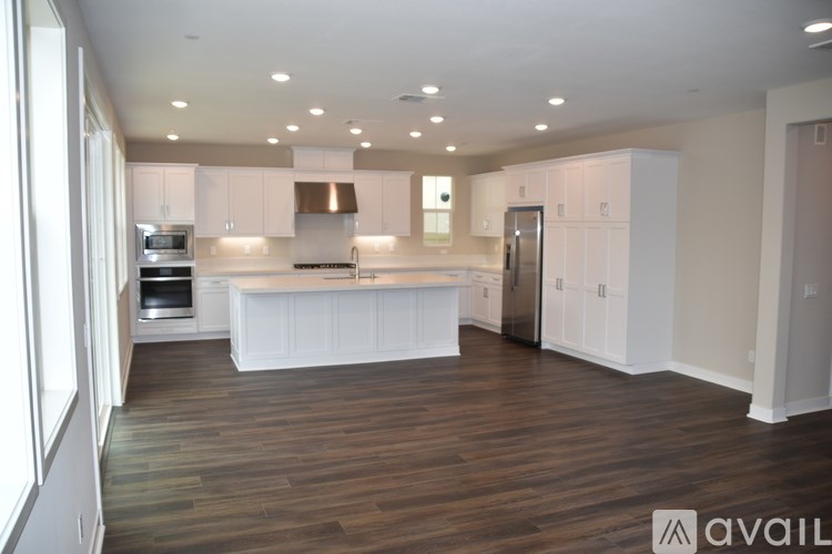 A spacious kitchen with white cabinets and a wooden floor.