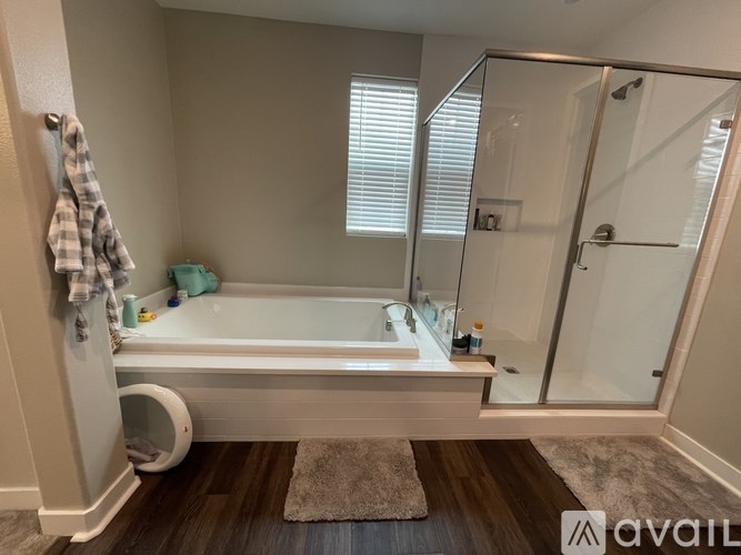 A bathroom with a bathtub, a towel, and a glass shower door.