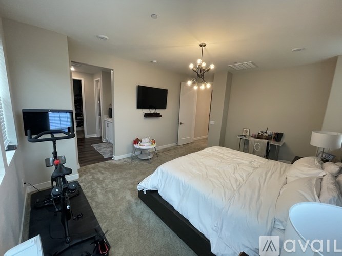 A bedroom with a large bed and a television mounted on the wall.