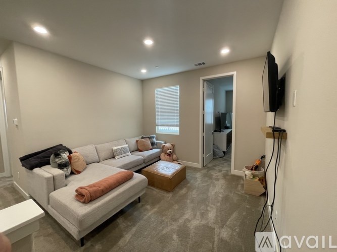 A living room with a grey sofa and a television on the wall.