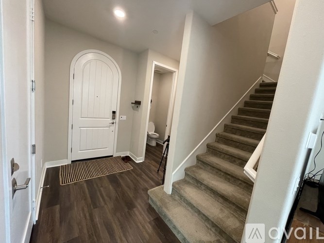 A hallway with a staircase and a white door.