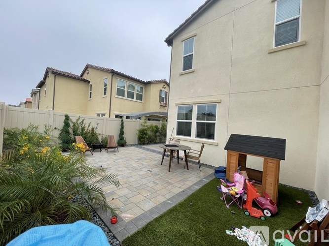 A backyard with a patio, a table, chairs, and a playhouse.